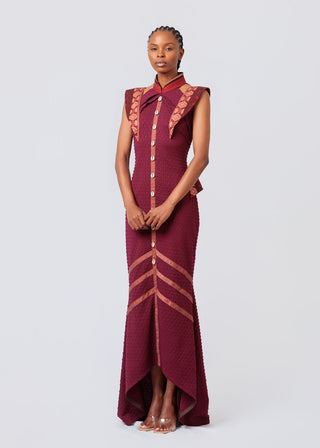 Woman wearing a Maroon dress with intricate patterns on a white background