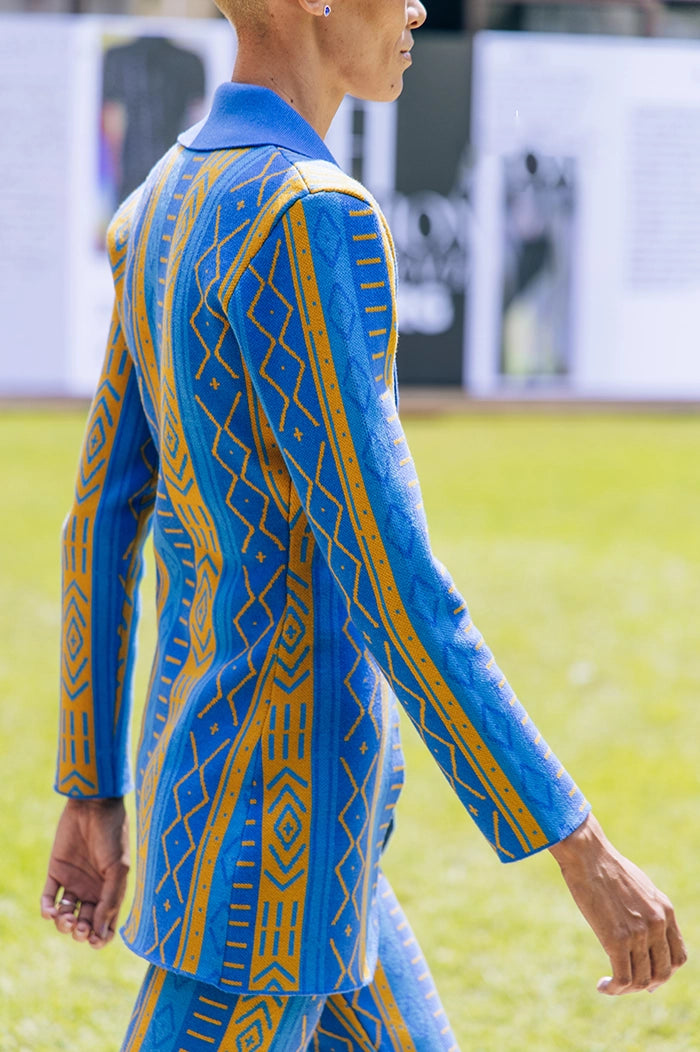 A person wearing a blue and yellow knit jacket with geometric patterns.