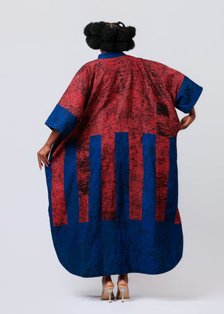 Person wearing a long, patterned dress with Burgundy and blue vertical stripes on a white background