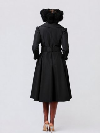 Person wearing a black coat with a belt on a white background