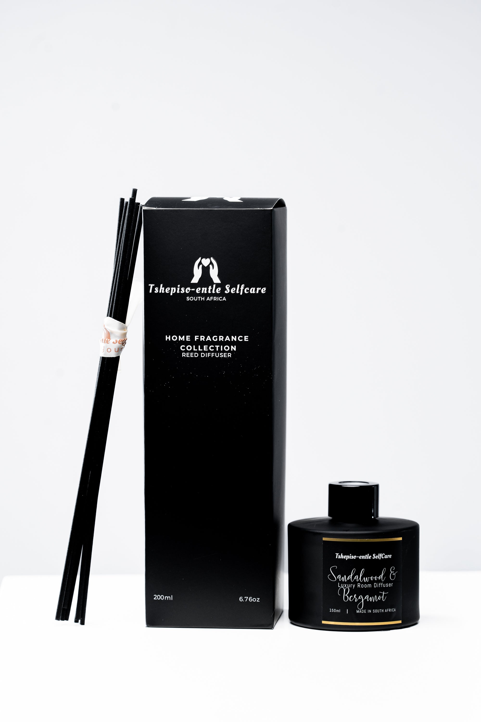Black home fragrance collection with diffuser and packaging on a white background