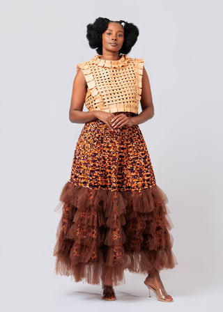 Woman wearing a stylish outfit with a textured top and ruffled skirt on a white background