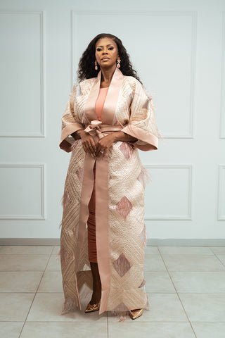 Woman wearing a patterned kimono-style outfit against a white wall.