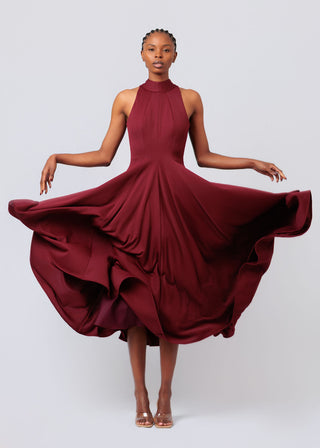 Woman wearing a burgundy dress with a flowing skirt on a light gray background