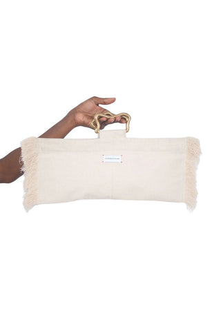 Beige clutch with gold handle held by a hand on a white background