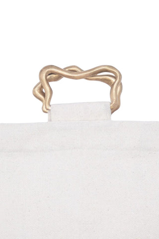Close-up of a white candle with a gold metallic candle wick trimmer on a white background