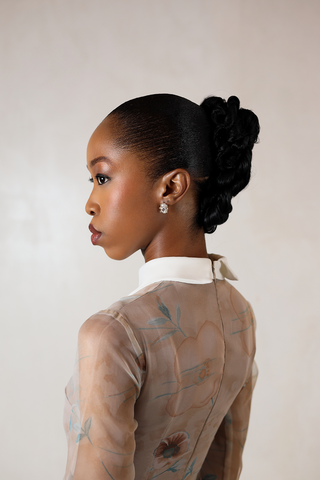 Woman with styled hair wearing a sheer collared dress with floral patterns.