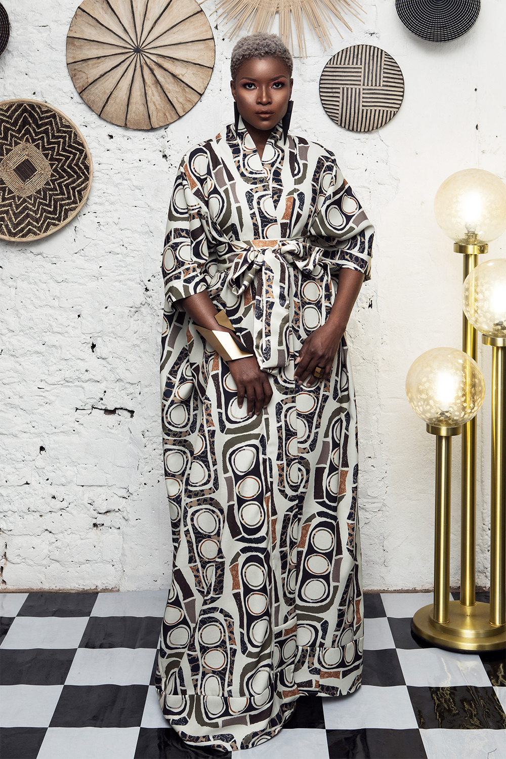 Woman in a patterned dress standing in a room with decorative wall art and a checkered floor sold at House of NALA