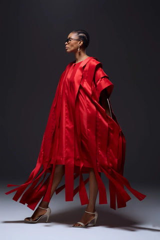 Side view of Model wearing red flowy dress styled with white heel open toe shoe