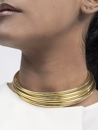 Close-up of a person wearing a gold necklace on a white background