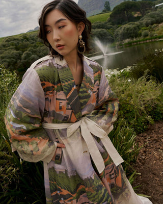 Woman in a colorful Linen Trench Coat standing in a natural setting with a lake and greenery for House of NALA