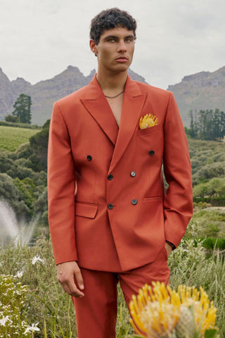 Man in a suit orange standing in a natural setting with mountains and greenery available at House of NALA