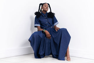 Woman wearing a denim skirt and shirt sitting on a white floor with a white wall background