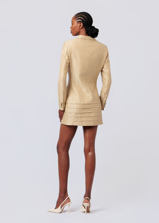 Woman wearing a beige leather jacket and skirt set on a light gray background