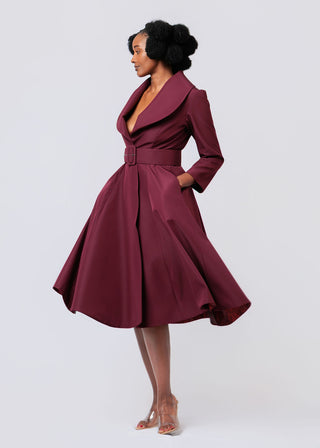 Woman wearing a burgundy dress with a belt on a white background
