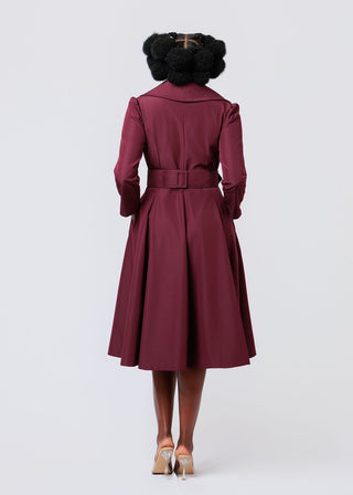 Person wearing a burgundy trench coat dress on a white background