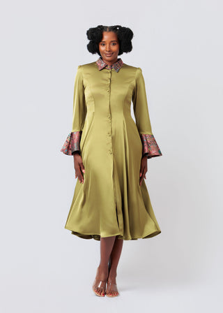 Woman wearing a green dress with patterned cuffs on a white background