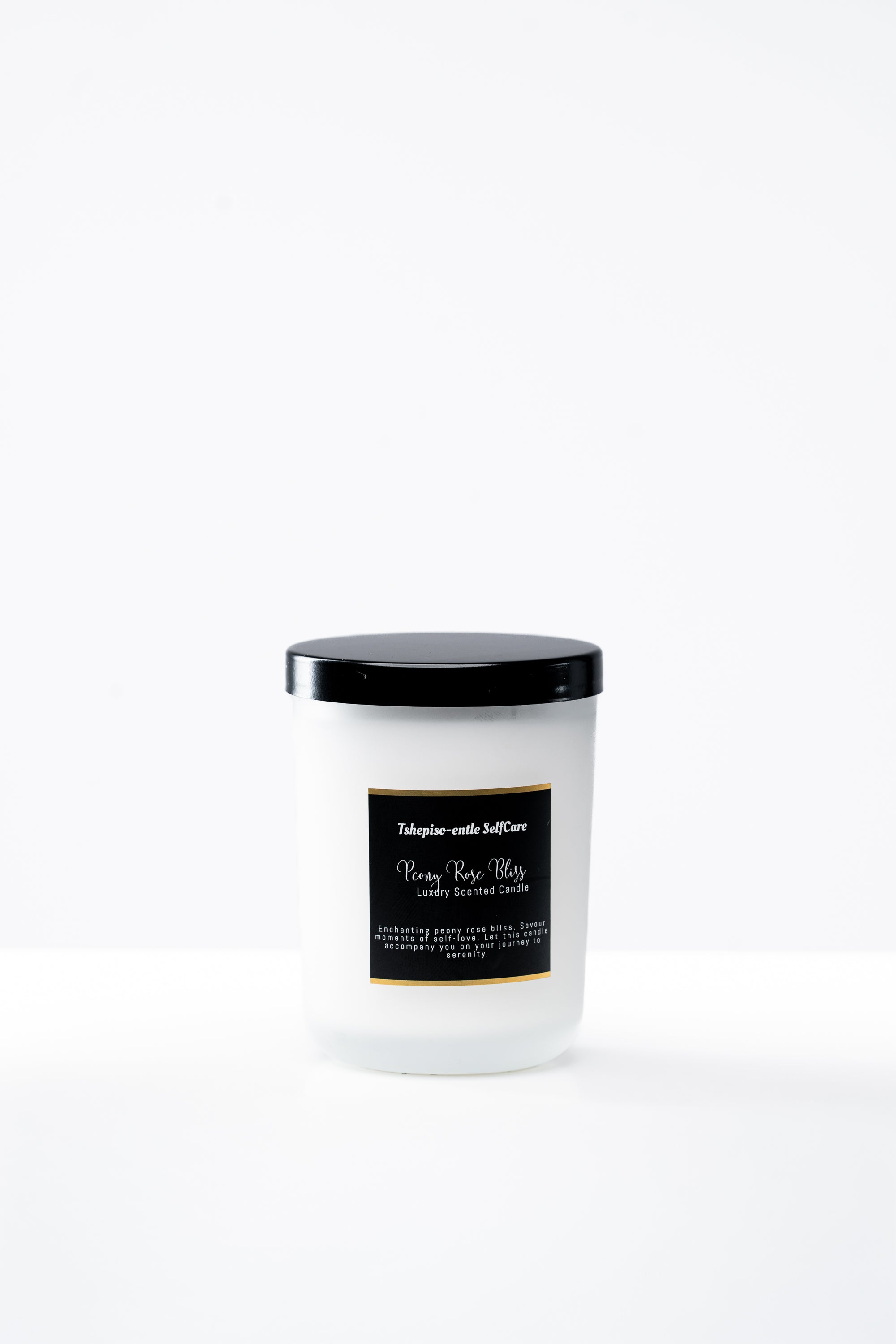 White candle with a black lid and label on a white background