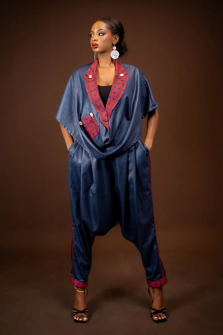 Woman wearing a blue jumpsuit with red accents against a brown background