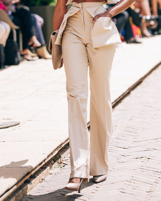 A person wearing beige cargo suit pants walking on a cobblestone street.