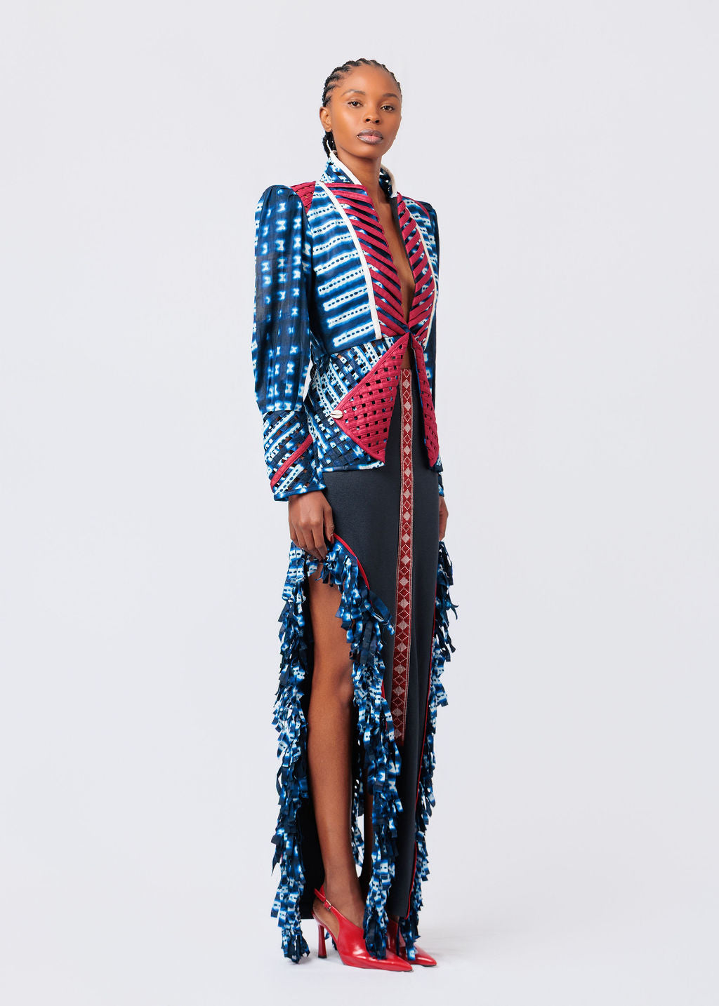 Woman wearing a colorful patterned dress with a high slit on a white background