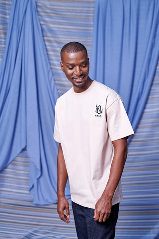 Man wearing a white t-shirt with a logo in front of blue curtains