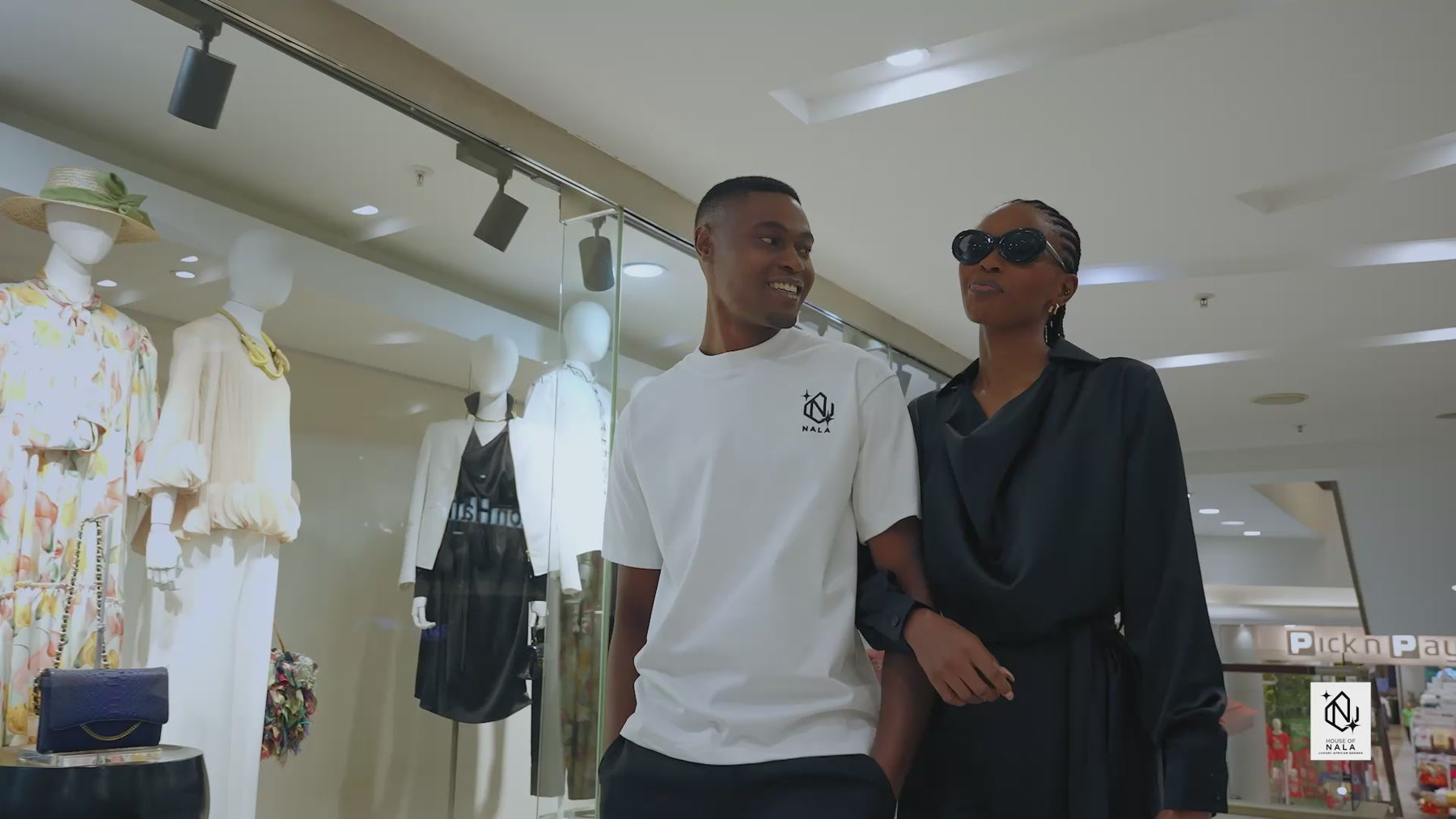 A shopping video , two shoppers come in and are met by the shop assistant. They try on clothes. Cheers Champagne and Leave rhe shop satisfied with shopping bags 